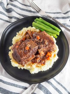 a black plate topped with meat and mashed potatoes