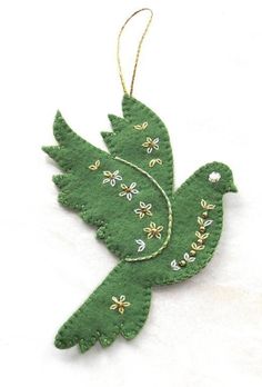 a green bird ornament hanging on a white background with gold stars and beads