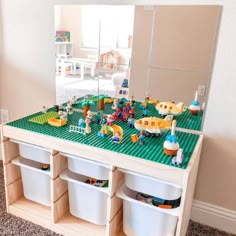 a toy table with legos on it in front of a mirror and some bins