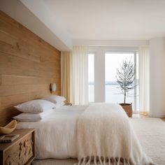 a bedroom with a bed, dresser and window overlooking the water in front of it