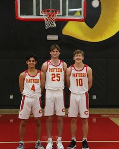 three young men standing next to each other in front of a basketball hoop with the number 25 on it