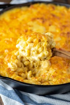 a skillet filled with macaroni and cheese being scooped from the casserole