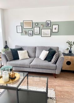 a living room filled with furniture and framed pictures on the wall above it's coffee table