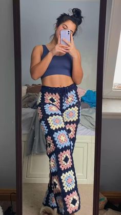 a woman taking a selfie in front of a mirror wearing crochet pants