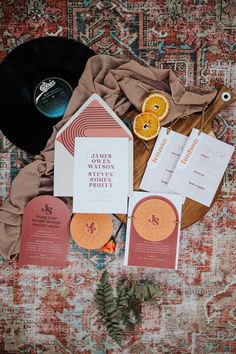 the wedding stationery is laid out on top of an old rug with orange slices