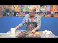 a man in an apron is making art work on a table with paint and paper