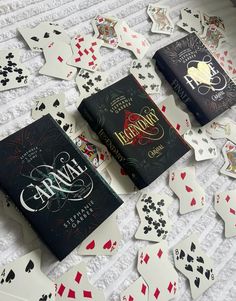 playing cards scattered around two books on a bed