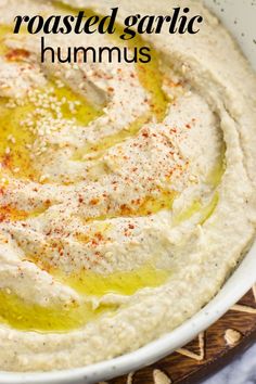 hummus in a white bowl with olive oil and parsley on the side, text reads roasted garlic hummus