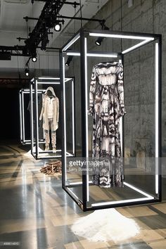 mannequins are displayed in an empty room with light from overhead lamps on the floor