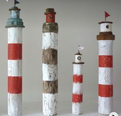 four wooden lighthouses are lined up in a row and one is painted red, white and blue