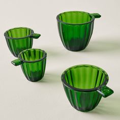 three green glass cups with handles on each one and two in the middle, sitting next to each other