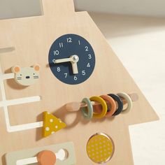 a wooden clock with different shapes and sizes on it's face, sitting next to other toys