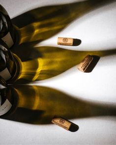 three bottles of wine sitting next to each other on a white counter top with shadows from them