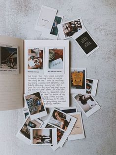 an open book sitting on top of a table covered in pictures and photos next to a notebook