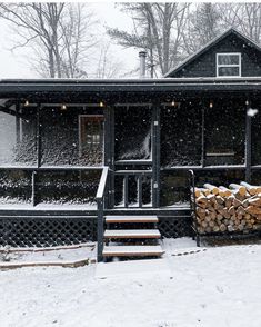 a cabin with snow falling on the roof and steps leading up to it