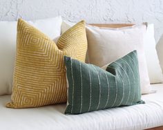 three pillows sitting on top of a white couch