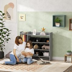 a woman and child sitting on the floor in front of a book shelf