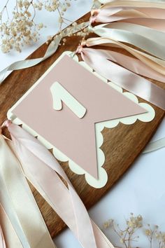 a wooden cutting board topped with ribbon and a cut out of the letter f on it