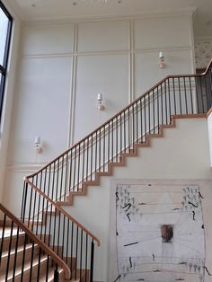 a staircase leading up to a painting on the wall in a room with white walls