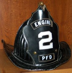 a black fireman's helmet with the number 2 on it sitting on a shelf