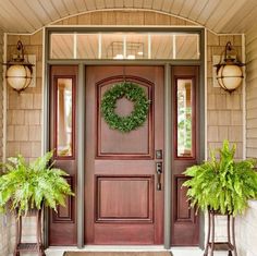 the front door is decorated with wreaths and potted plants