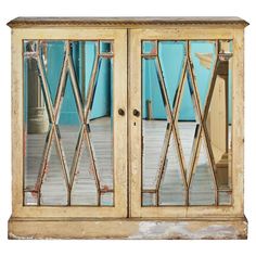 an old wooden cabinet with glass doors on the front and back sides, against a blue wall