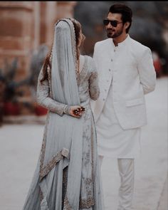 a man and woman dressed in white standing next to each other on the street together