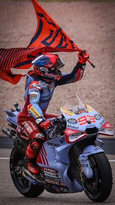 a man riding on the back of a motorcycle holding a red and blue flag over his head