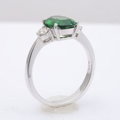 This oval cut Tsavorite Garnet, set at the center of this ring steals the show. It’s rich green, has been highlighted by the perfectly matched round brilliant diamonds that rest on either side of the center stone. Eye clean and large in size, this 2.13 carat stone is a rare gem. Set in 18K white gold, this ring is just the right combination grace and beauty. Order online info@jupitergem.com Timeless Green Diamond Round Ring, Oval Tsavorite Diamond Ring For Formal Occasions, Timeless Green Brilliant Cut Ring, Timeless Green Diamond Ring With Brilliant Cut, Gia Certified Oval Green Diamond Ring, Brilliant Cut Oval Diamond Ring With Tsavorite, Green Oval Diamond Ring With Center Stone, Oval Tsavorite Ring With Center Stone, Oval Tsavorite Rings With Halo Setting