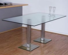 a glass table with two silver legs on the floor