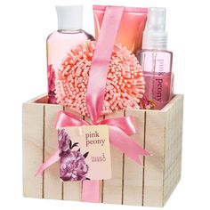 a wooden box filled with pink items on top of a white table next to a bottle of lotion