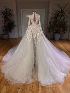 a white wedding dress with long sleeves and sheer tulle skirt on display in front of a