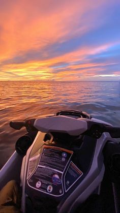 the back end of a boat in the water at sunset with clouds and blue sky