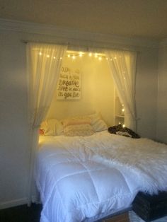 a bed with white sheets and lights on the headboard