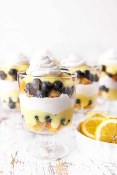 two desserts with lemon slices and blueberries in them on a white wooden table