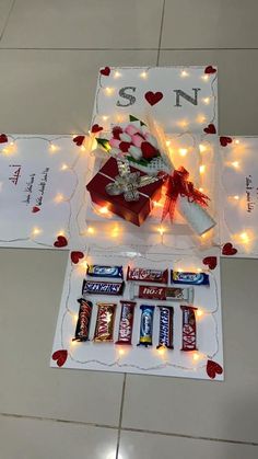 an assortment of candy and valentine's day treats on a table with lights in the background