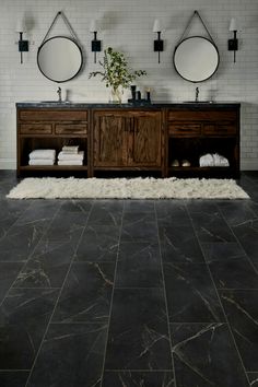 a bathroom with two sinks and mirrors on the wall next to a rug in front of it