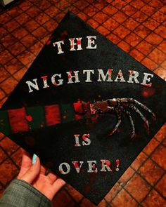 someone holding up a graduation cap that says the nightmare is over