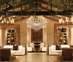 a living room with couches, chairs and a chandelier hanging from the ceiling