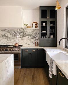 a kitchen with marble counter tops and black cabinets