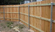 a wooden fence in front of a house with no grass on the ground next to it