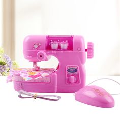 a pink sewing machine sitting on top of a white table next to a flower vase