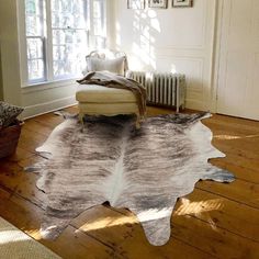 a living room with a chair and a cow hide rug on the floor in front of a window