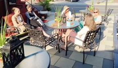 four women sitting at an outdoor table talking to each other