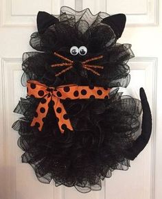 a black cat wreath with orange polka dots on it's face and eyes, hanging from the front door