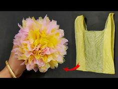 a hand holding a yellow shopping bag next to a pink and yellow flower