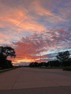 the sky is pink and blue as it sits in the middle of an empty parking lot