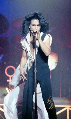 a man with long hair on stage holding a microphone