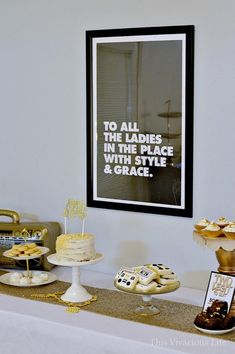 a table topped with cakes and desserts next to a framed poster