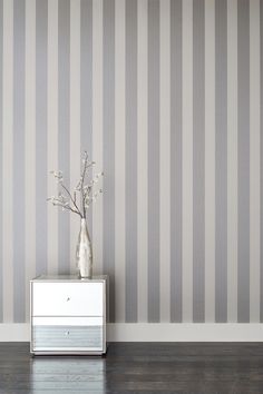 a vase with flowers in it sitting on a dresser next to a striped wallpaper